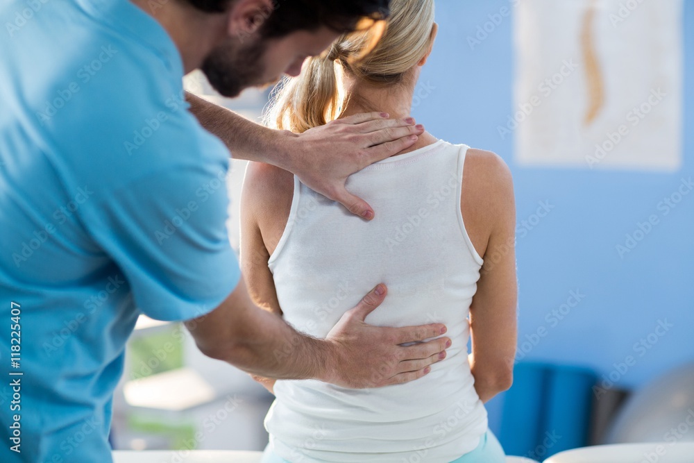 Male physiotherapist giving back massage to female patient